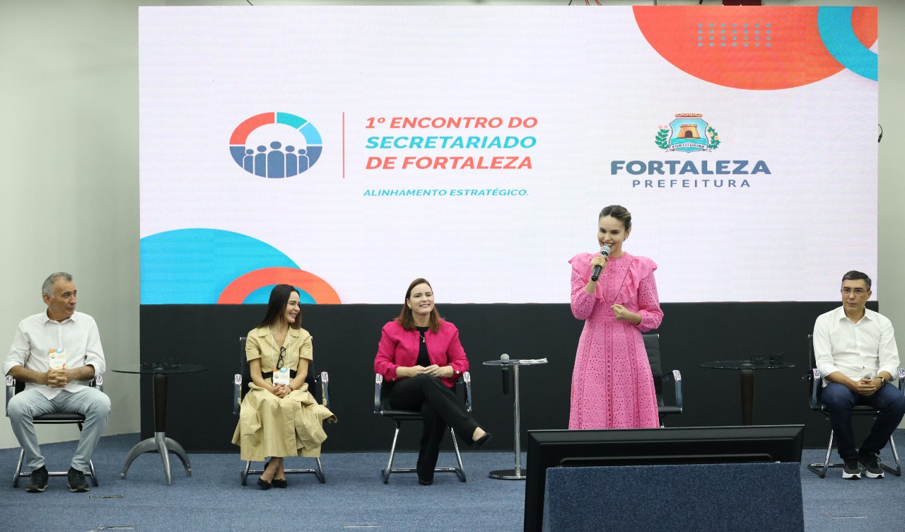 Gabriella Aguiar fala no palco do auditório do BNB. Ela está com um vestido rosa